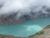 Der Ala-Kol See (3530 m) vom gleichnamigen Pass (3920 m) gesehen. Der Name Ala-Kol bedeutet "Bunter See". Das saubere Wasser spiegelt die Farbe des Himmels wider, die sich im Tagesverlauf ständig ändert. So zeigt sich auch der See im verschiedenfarbigen Gewand.